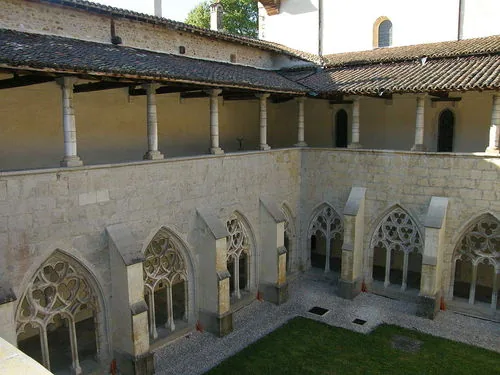 Cloître de l'abbaye d'Ambronay : arcades gothiques en pierre, galerie haute à colonnes et pelouse centrale